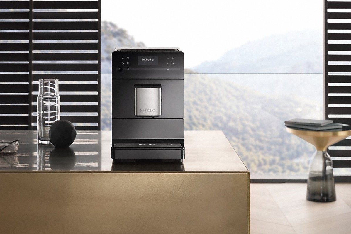 Miele CM5500 coffee machines in black and rose gold.Miele CM5500 coffee machine on kitchen countertop with scenic view.