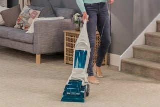 Person using Russell Hobbs carpet cleaner in living room.