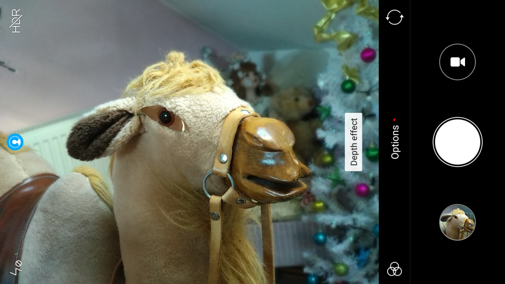 Xiaomi Mi A1 camera interface while photographing a toy horse.Rooftop view of residential area with clear skyPhoto taken by Xiaomi Mi A1 showcasing outdoor clarity.Decorated Christmas tree with lights and colorful ornaments.Close-up of a wooden horse toy with a leather harness.Close-up of a white and blue dreamcatcher with feathers.Close-up of a plush toy dog with fluffy white fur.