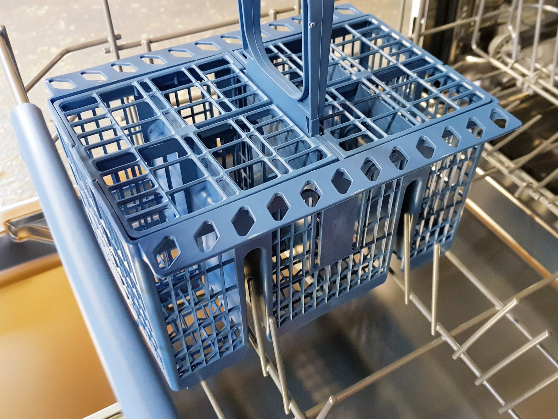 Blue cutlery basket inside an open dishwasher