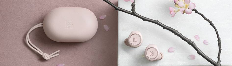 B&O Beoplay E8 earphones with charging case and decorative flowers.