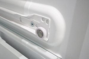 Close-up of Whirlpool refrigerator interior hinge mechanism.