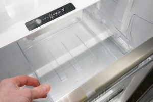 Whirlpool refrigerator interior with person's hand on drawer.