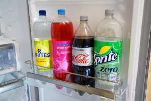 Bottled beverages on refrigerator shelf.