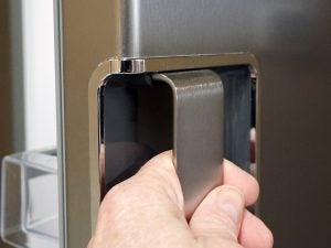 Close-up of hand opening Whirlpool refrigerator door.