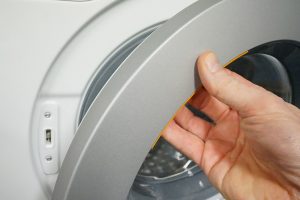 Hand opening a Miele WDB020 washing machine door.