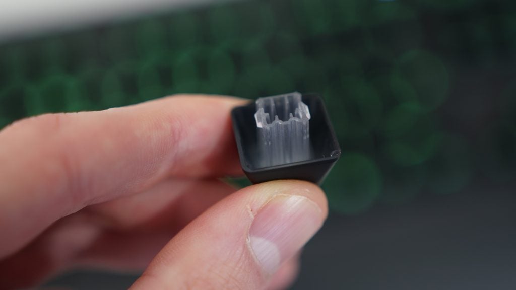 Close-up of a Logitech G213 keycap held between fingers.