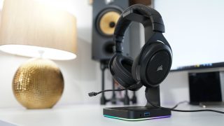 Corsair HS50 gaming headset on a desk with speakers in background.