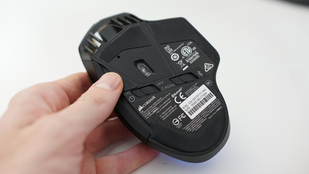 Hand holding Corsair Dark Core RGB SE gaming mouse underside.