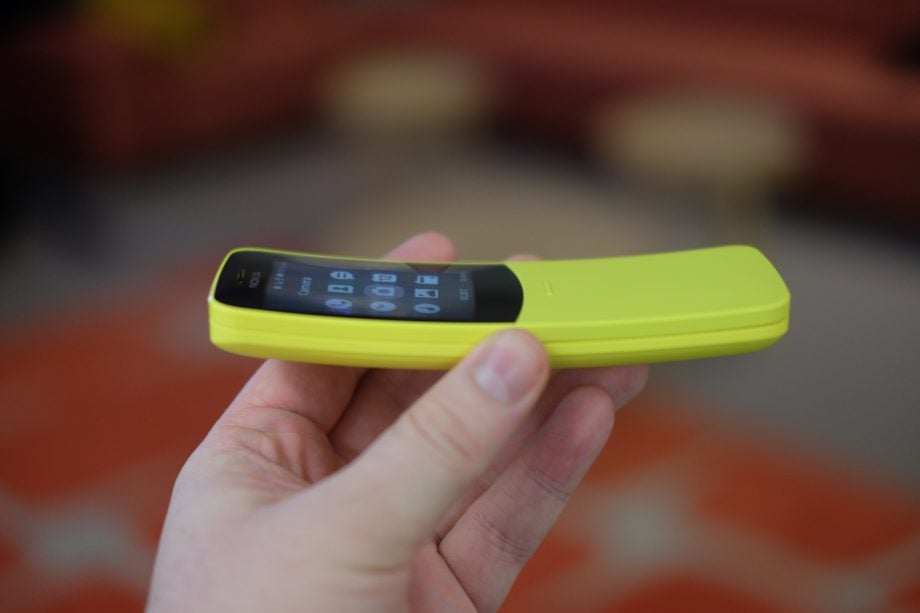 Hand holding a yellow Nokia 8110 4G phone.