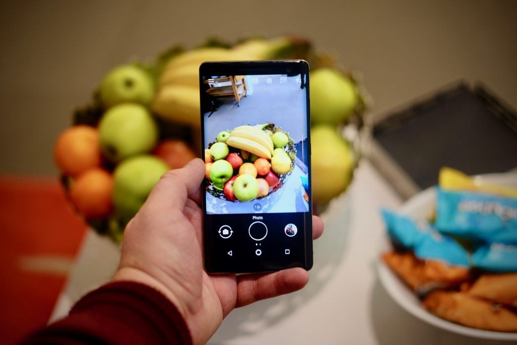 Hand holding Nokia 8 Sirocco taking photo of fruit bowl.