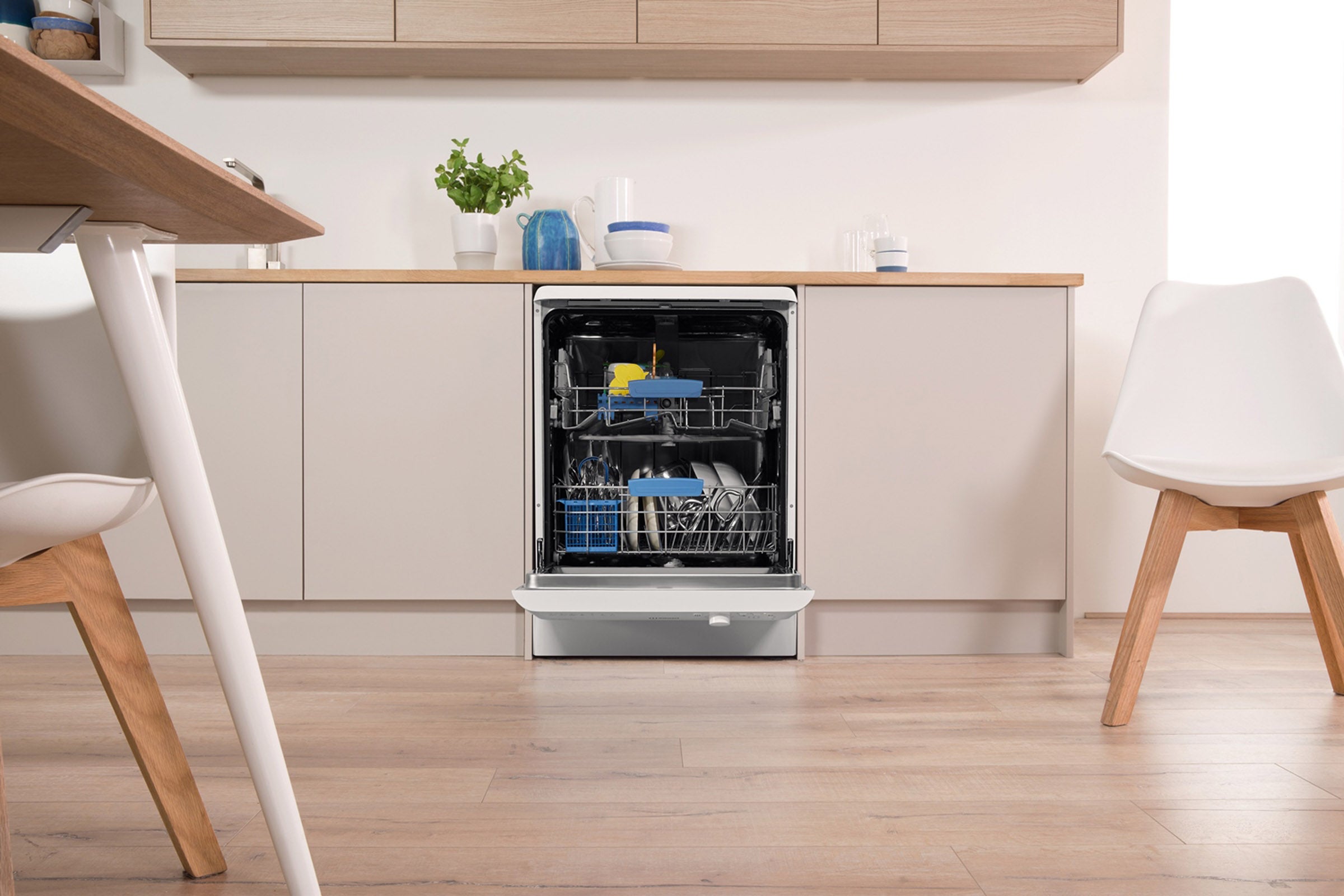 Indesit dishwasher open with clean dishes in kitchen.Indesit dishwasher integrated in a modern kitchen setup.