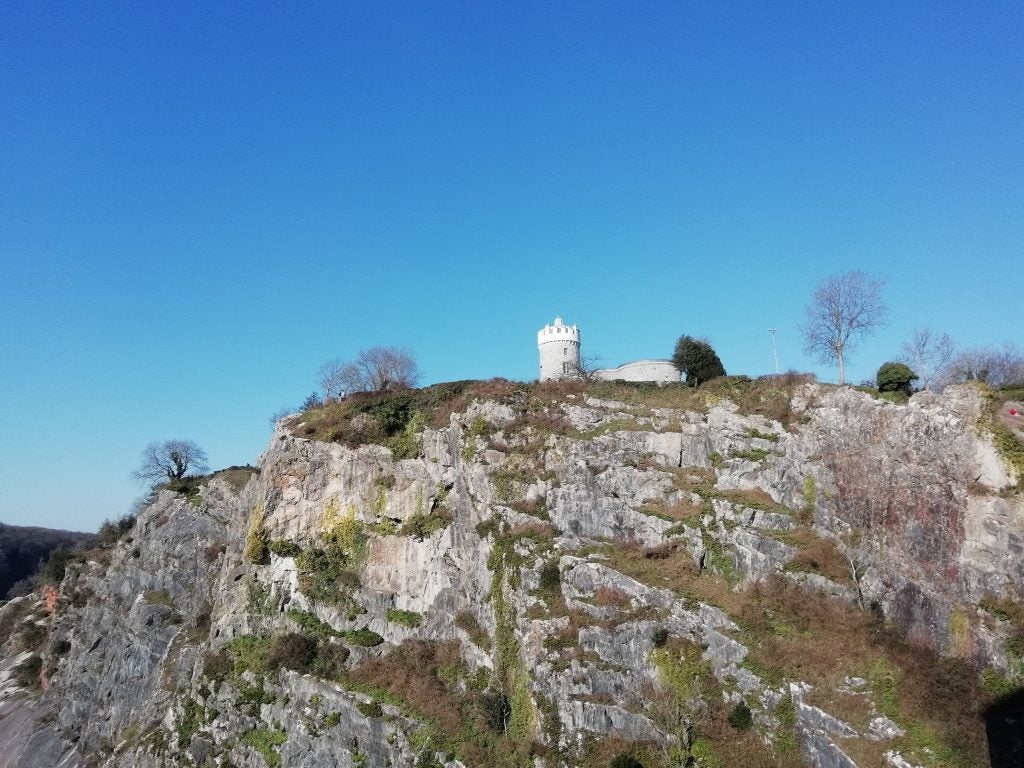 Scenic landscape with a tower on a rocky hill under blue sky