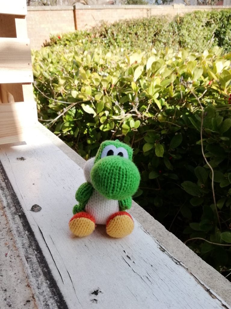 Street scene captured by Honor 9 Lite camera.Knitted green and white toy sitting on wooden beam