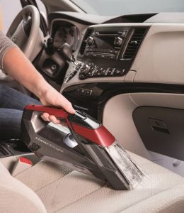 Person using Bissell Stain Eraser on car upholstery.
