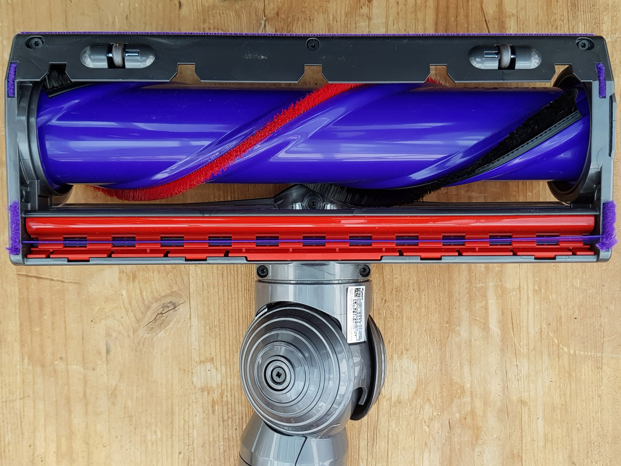 Dyson Cyclone V10 vacuum cleaner head on wooden floor.