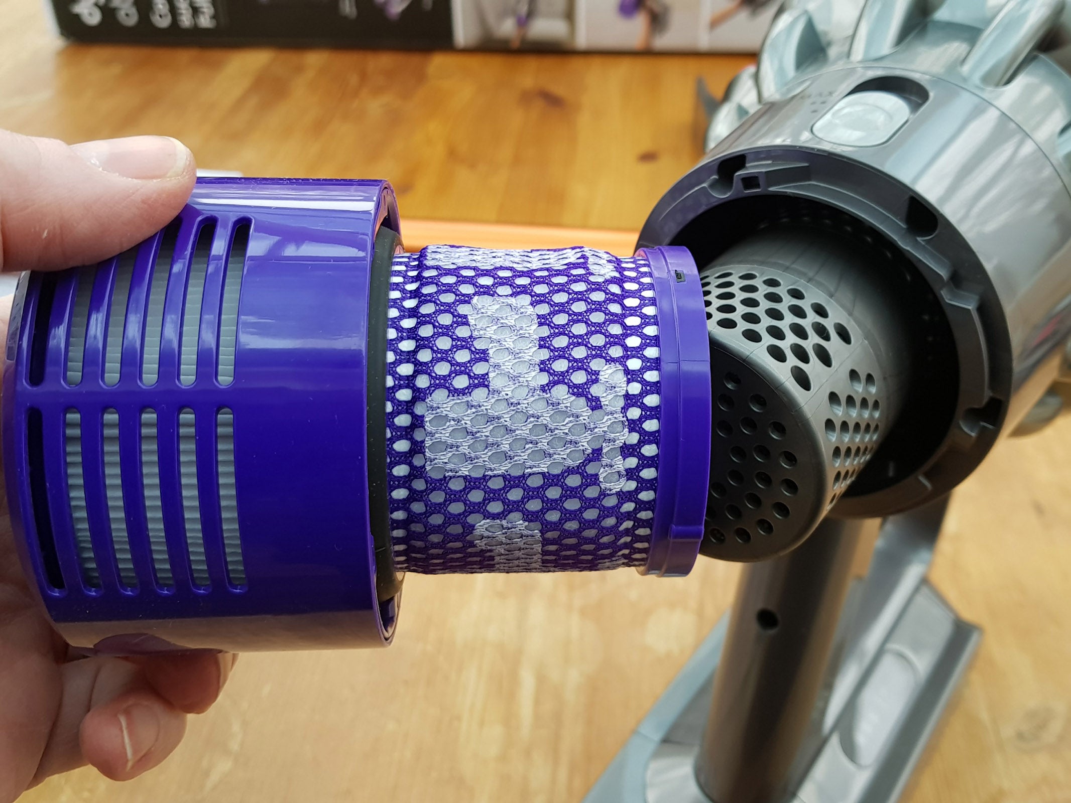 Hand holding Dyson Cyclone V10 vacuum filter and bin.