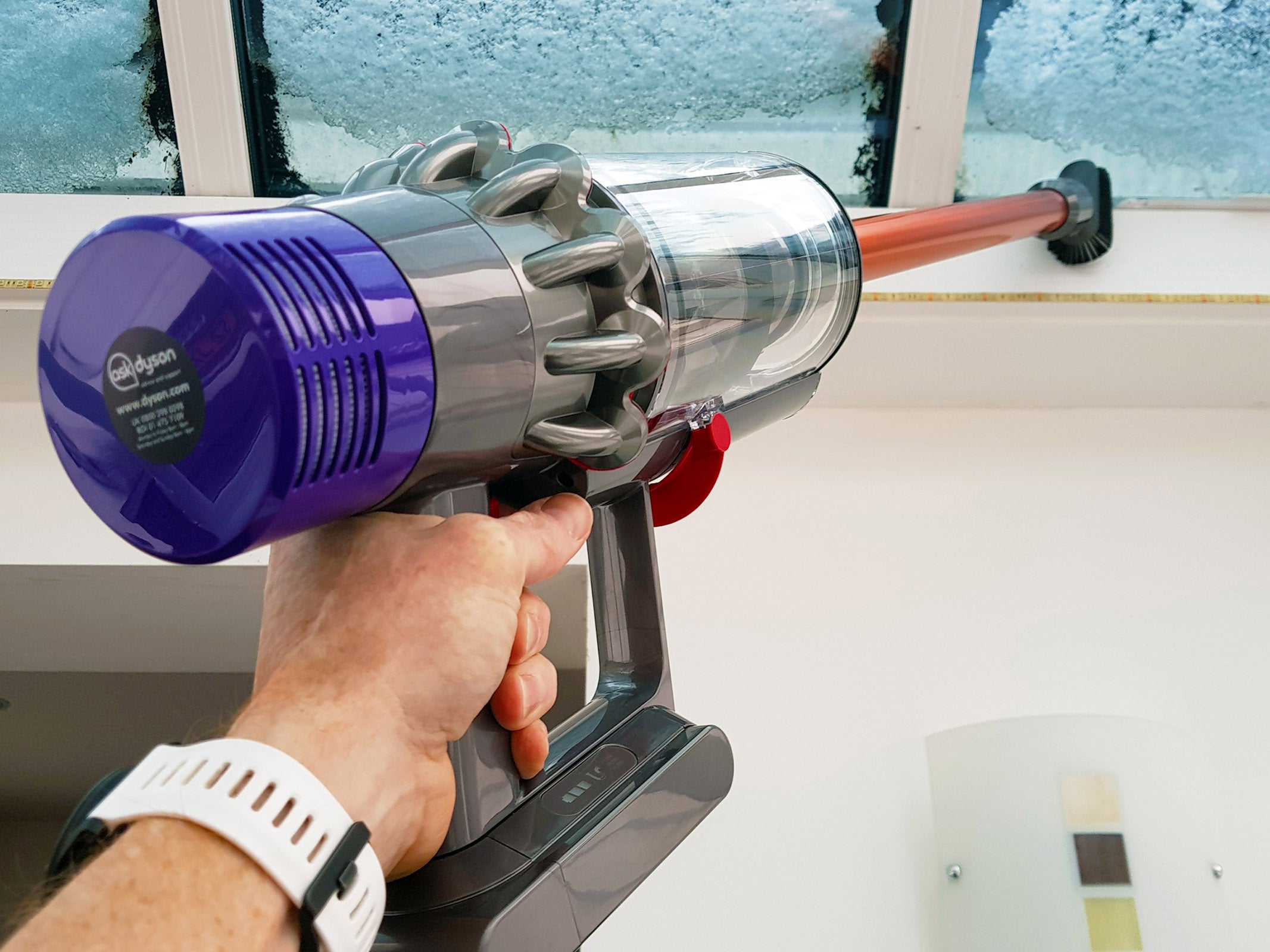 Hand holding Dyson Cyclone V10 Absolute vacuum cleaner.