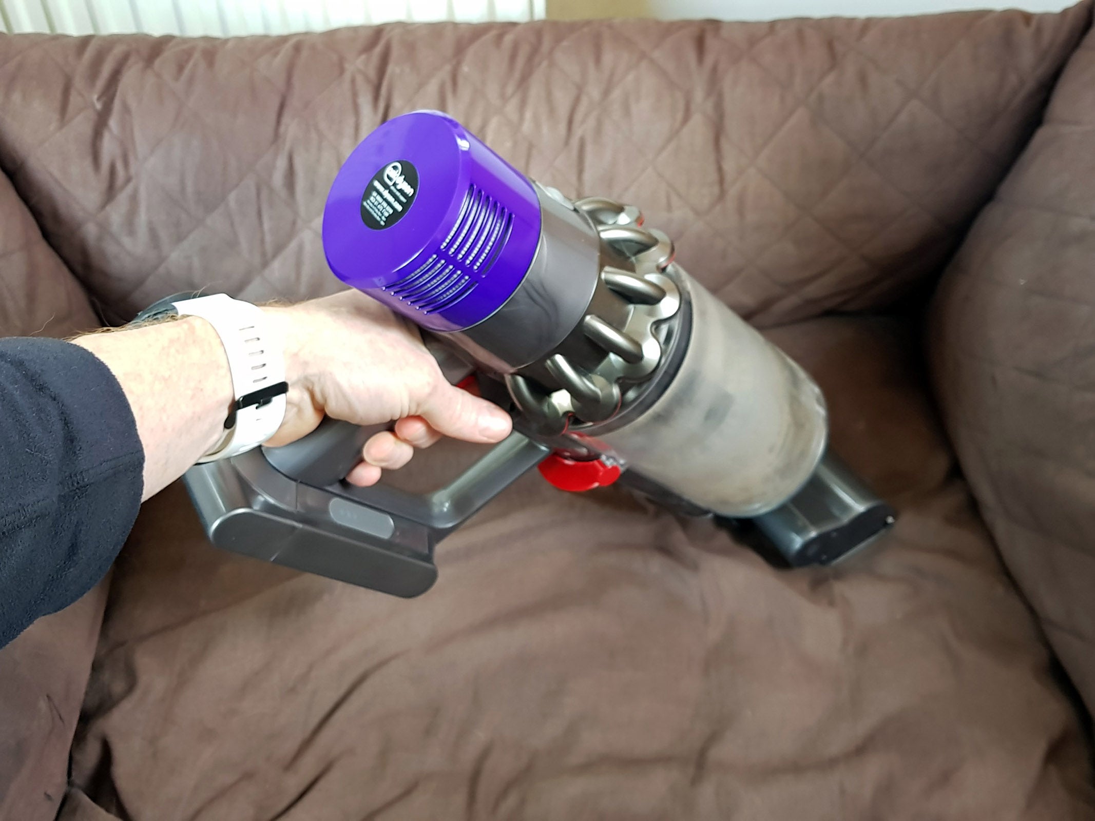 Person holding a Dyson Cyclone V10 handheld vacuum.
