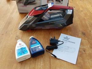 Bissell Stain Eraser cordless cleaner with cleaning solutions and user guide.