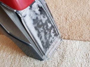 Bissell Stain Eraser cleaning a carpet with suds visible.
