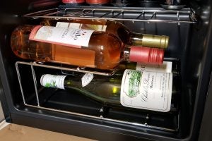 Wine bottles stored in Currys Essentials wine cooler racks.