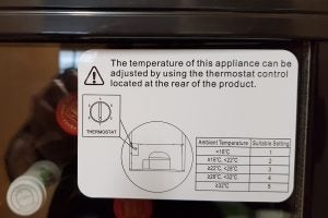 Instruction label for adjusting thermostat on Currys Essentials appliance.