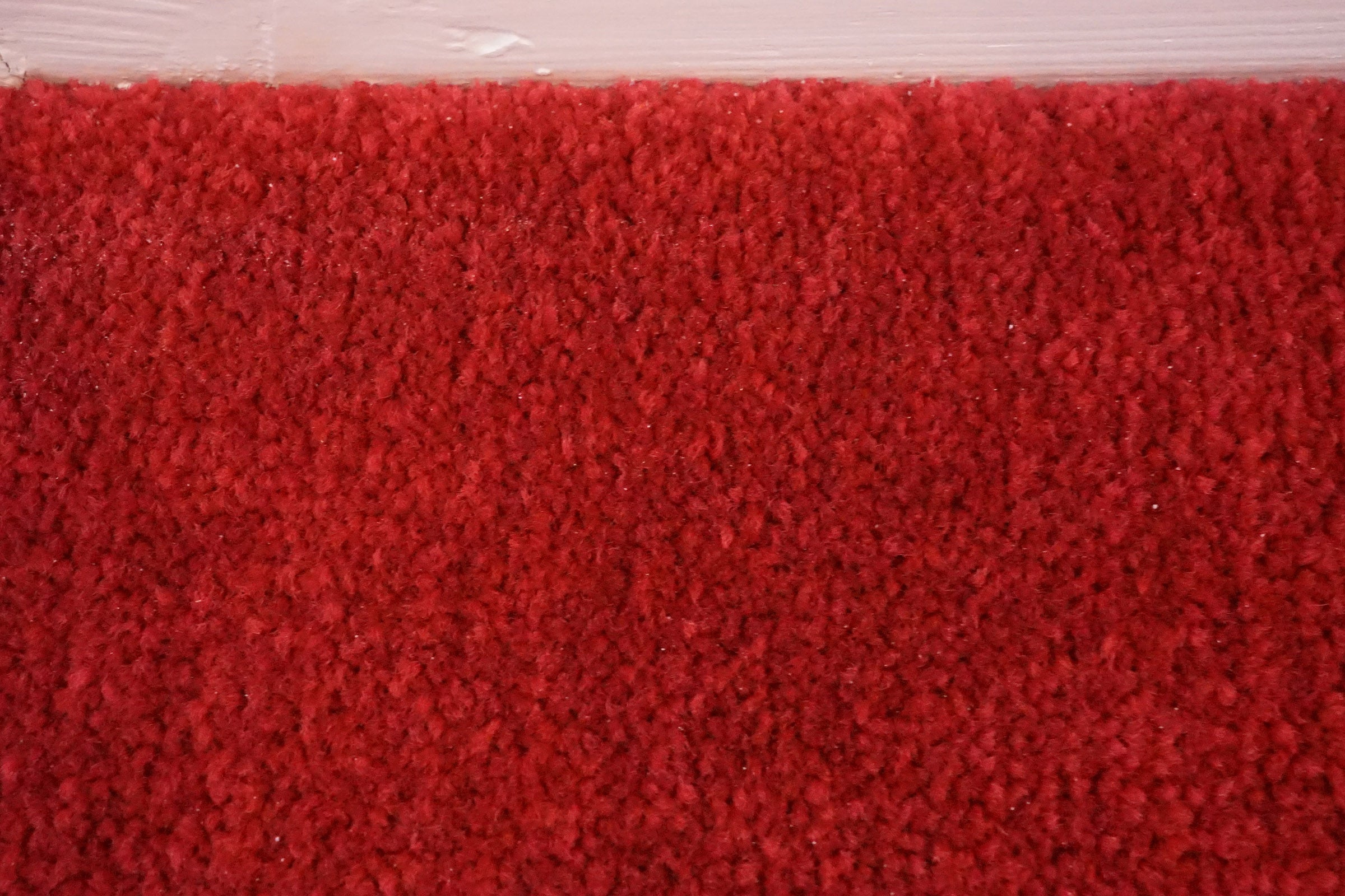 Close-up texture of red carpet flooringCarpet with clean and dirty halves demonstrating vacuum cleaner efficacy.