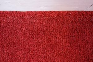 Red carpet texture with sparkling granules close-up.