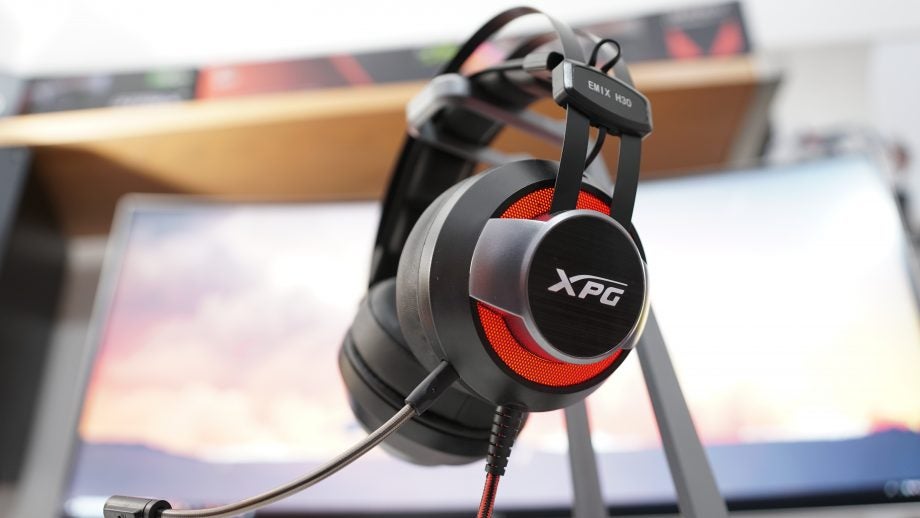 XPG Emix H30 gaming headset on a stand with blurred background.