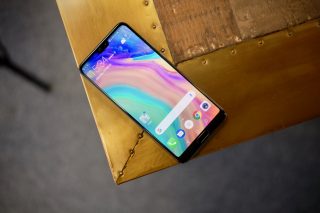 Huawei P20 Pro smartphone on wooden table with screen on.