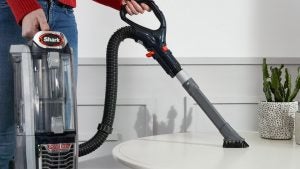 Person using Shark DuoClean vacuum cleaner in home setting.