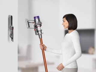 Woman holding a Dyson Cyclone V10 vacuum cleaner.