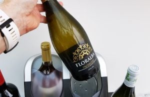 Hand placing bottle in Hostess wine cooler.