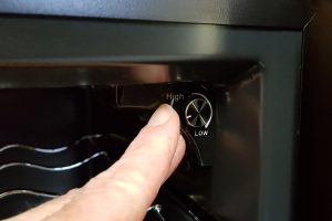Finger adjusting temperature knob on Baumatic wine cooler.