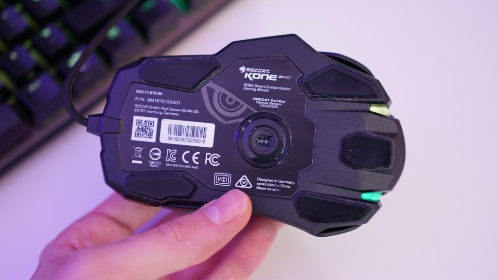 Hand holding Roccat Kone Aimo gaming mouse upside down showing sensor.