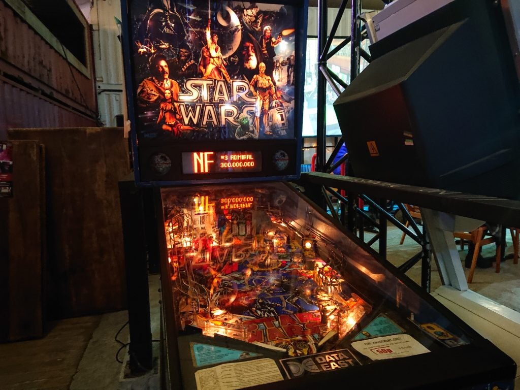 Star Wars-themed pinball machine in an arcade settingLow-light photo of a busy bar interior captured by a camera.