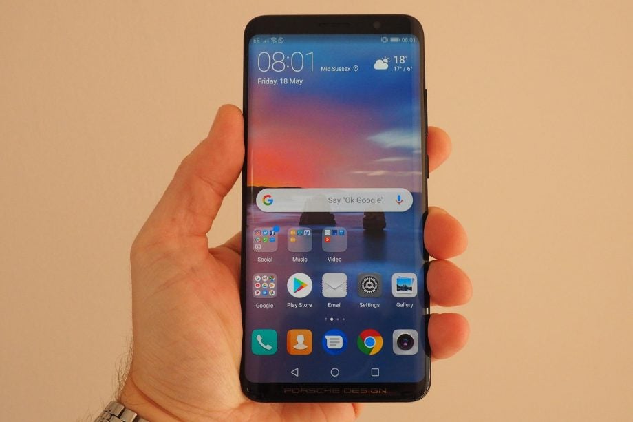 Hand holding Huawei Mate RS smartphone displaying home screen.