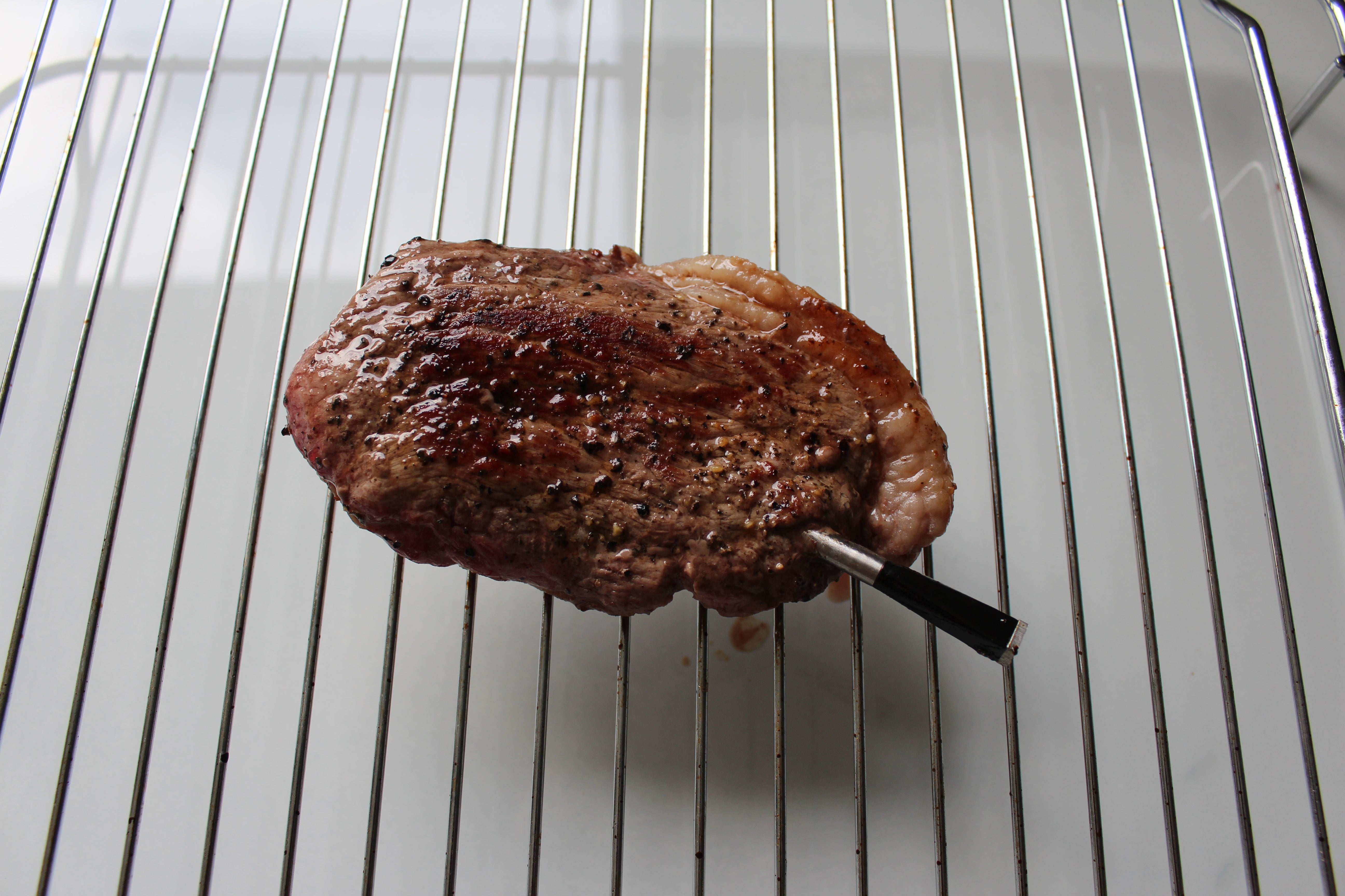 Grilled steak with Meater Probe thermometer inserted.