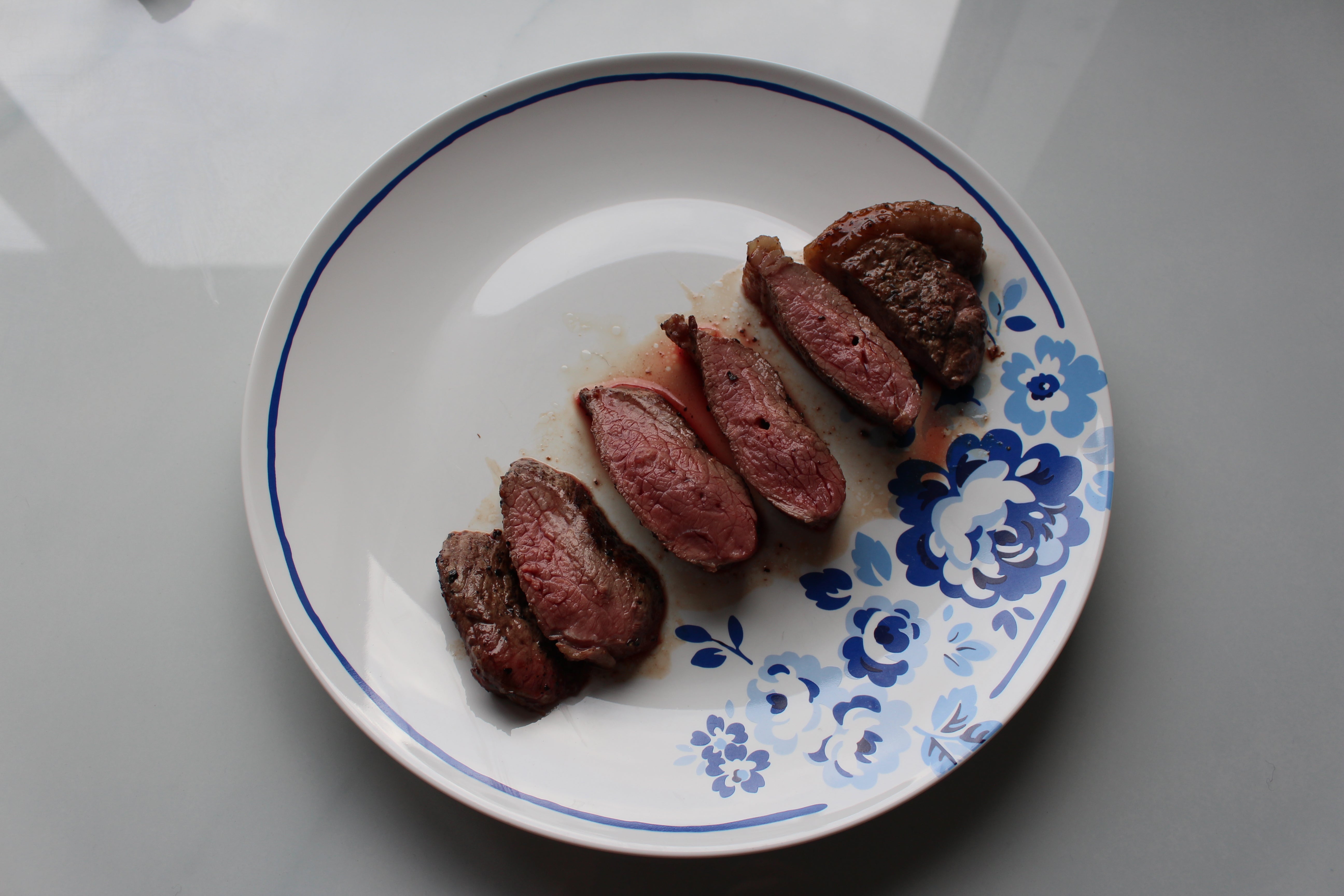 Sliced steak on a plate showing doneness levels.