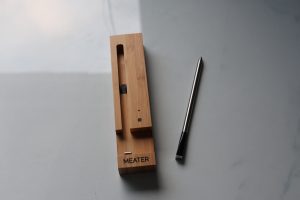Meater wireless thermometer with its wooden charging case.
