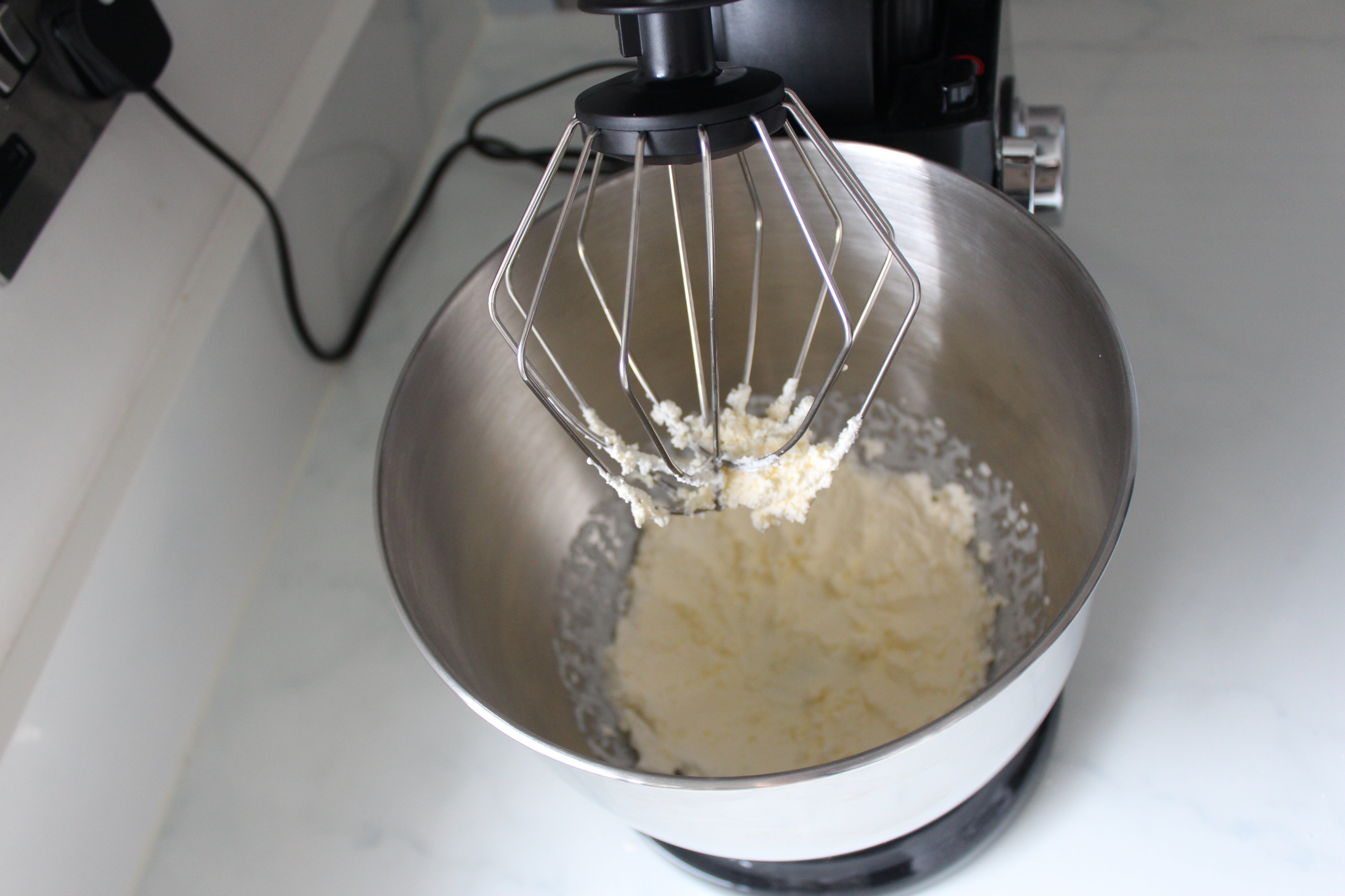 Vitinni stand mixer mixing dough with whisk attachment.
