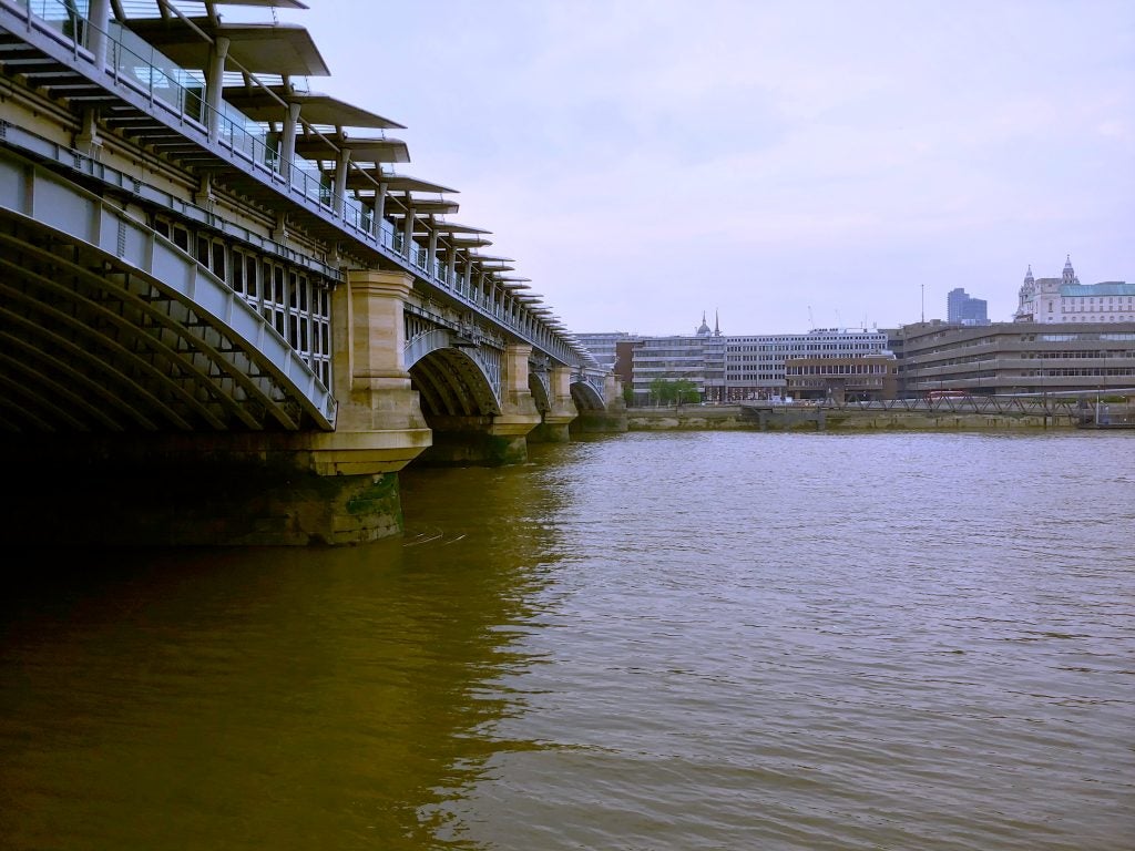 River scene with a bridge and buildings in overcast weather.Photograph of a bridge over a river with buildings in the background.