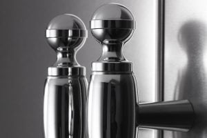 Stainless steel salt and pepper shakers against refrigerator door.