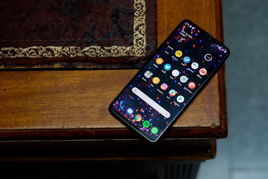 OnePlus 6 smartphone with display on wooden table.