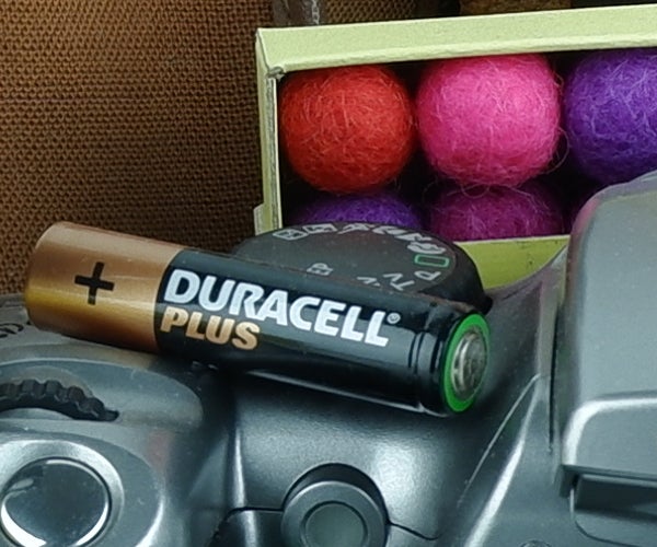 Duracell battery on Fujifilm X-A5 camera with colorful balls background.