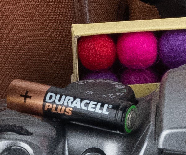 Duracell battery on top of a camera near colorful balls.