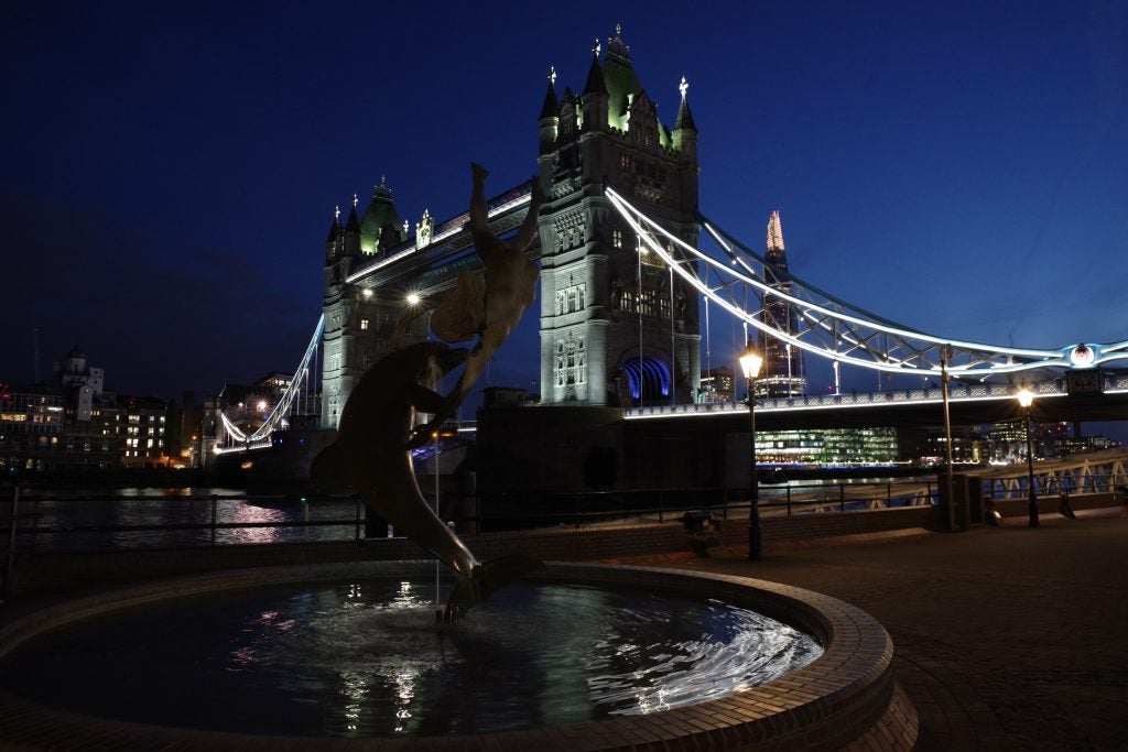 Night shot of Tower Bridge with statue and lights reflections.