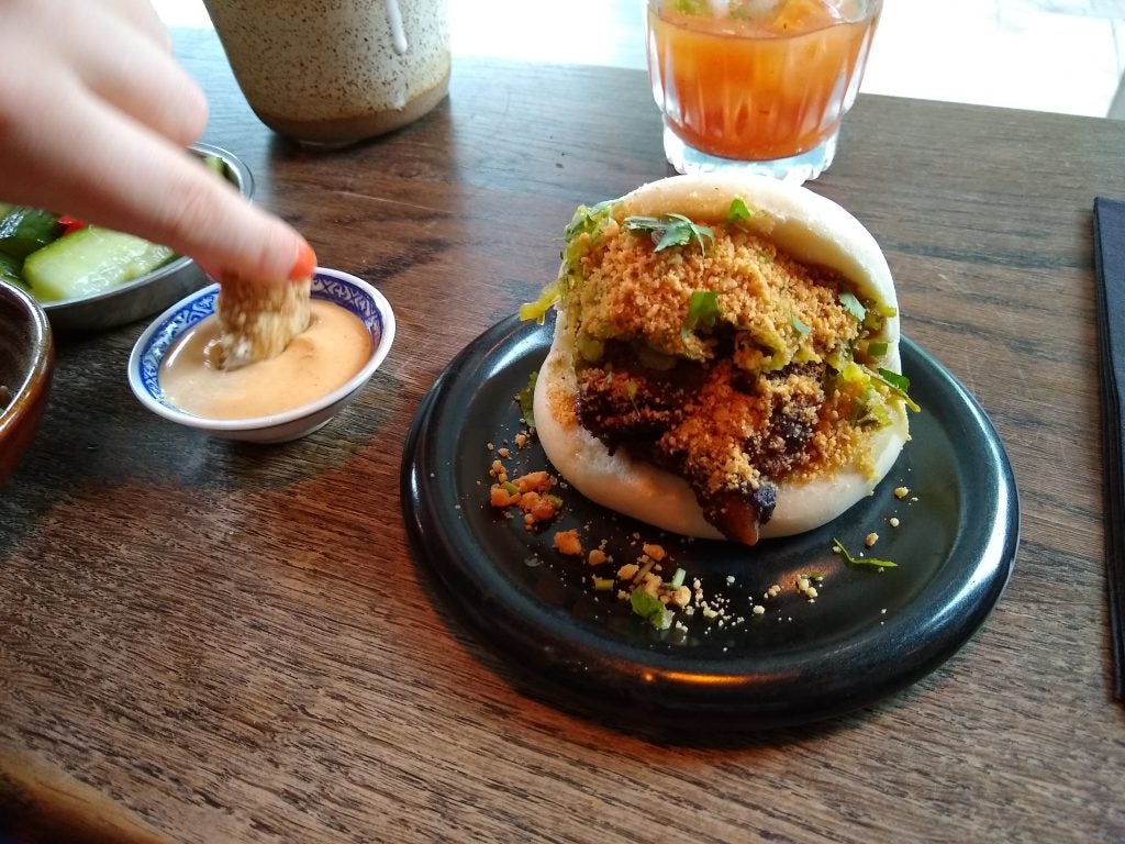 Person dipping food in sauce at a table.