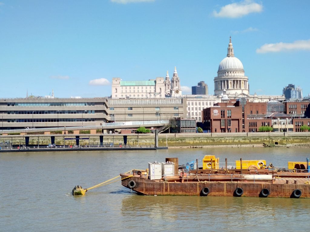 Clear day photo of St. Paul's Cathedral across the Thames River.